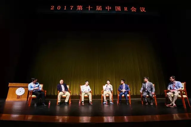 七位嘉宾分坐在舞台上的椅子上进行圆桌讨论。