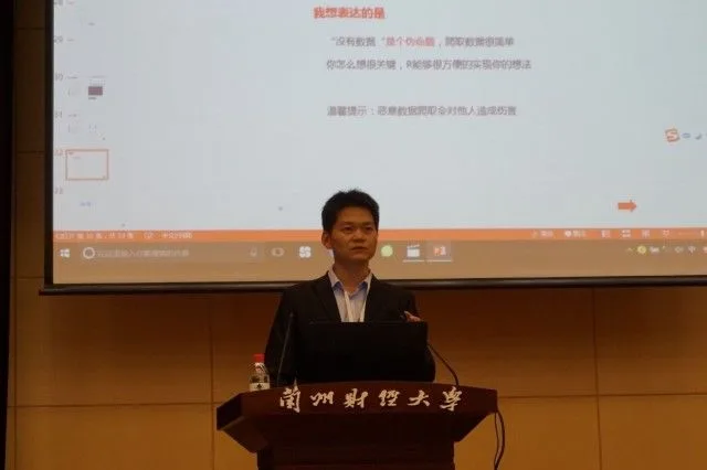 一名发言者站在兰州财经大学讲台后，身后显示总结幻灯片。