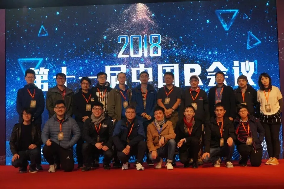 二十余名参会者在写有2018中国R会议的蓝色舞台背景前合影。