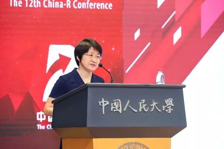 一名发言者站在中国人民大学讲台后，背景为红色会议主视觉。