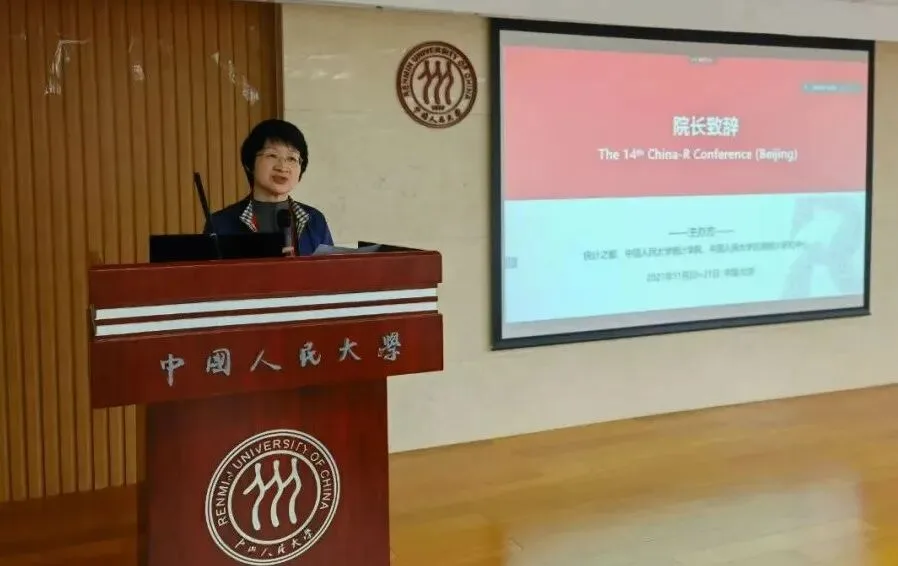 一名发言者站在中国人民大学讲台后，旁边屏幕显示院长致辞标题。