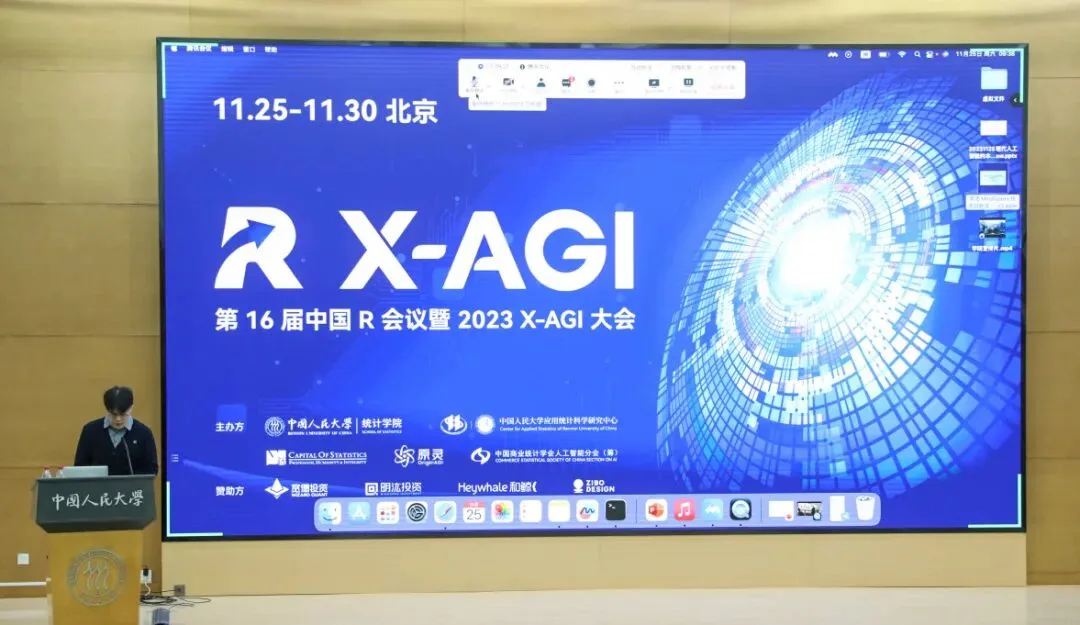 发言者站在大型蓝色X-AGI会议主视觉屏幕旁的讲台上。