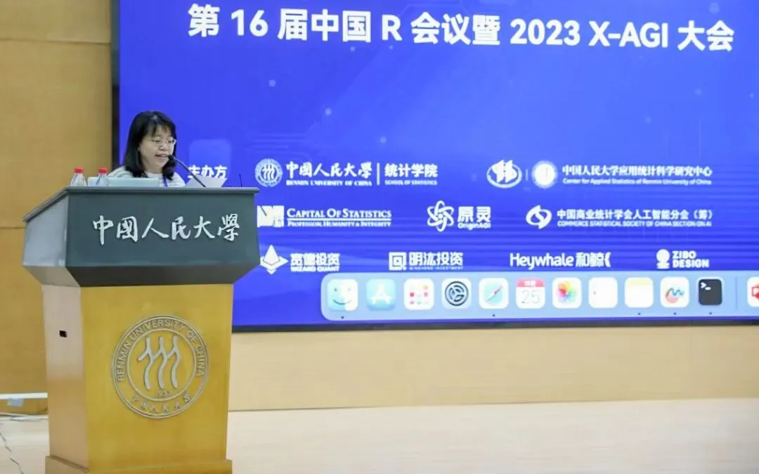 一名发言者站在中国人民大学讲台后，蓝色屏幕显示会议名称与主办信息。